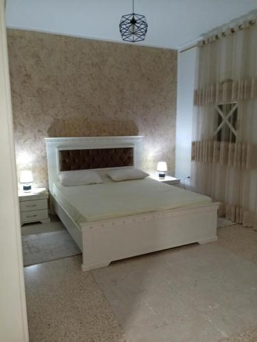 a bedroom with a white bed and two night stands at Dar Yassine in Sahline