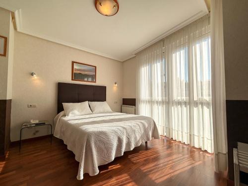 a bedroom with a bed and a large window at Hotel Verdemar in Ribadesella