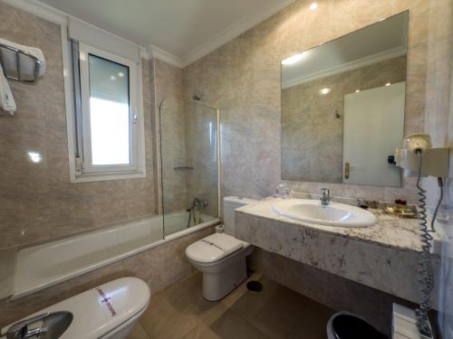 a bathroom with a sink and a toilet and a mirror at Hotel Verdemar in Ribadesella
