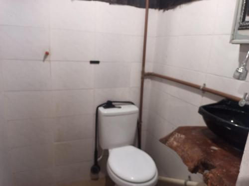 a bathroom with a white toilet and a sink at Suíte Albergue em Casa de Excursão in Cabo Frio