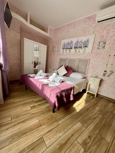 a bedroom with two beds with pink walls and wooden floors at Paganino rooms in Fiumicino