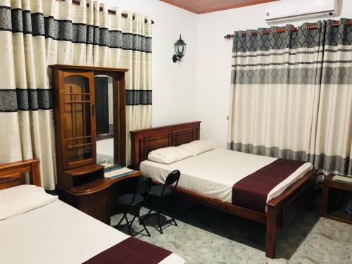 a bedroom with two beds and a desk and a mirror at Singhe Holiday Bungalow in Nikawatawana