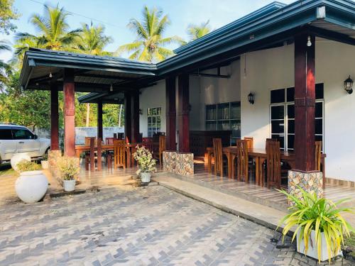 a restaurant with wooden chairs and a building at Singhe Holiday Bungalow in Nikawatawana
