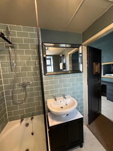a bathroom with a sink and a shower and a tub at The Q Hotel in Shanklin