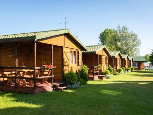 a row of cottages in a yard with green grass at Domki Anetta in Dąbki