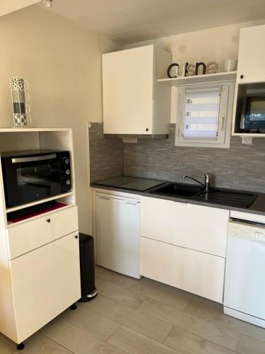 une cuisine avec des armoires blanches et un évier dans l'établissement Appartement avec piscine Arzon, à Arzon