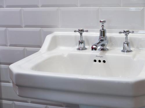 a white bathroom sink with two faucets on it at The Bryntirion Inn in Llandderfel