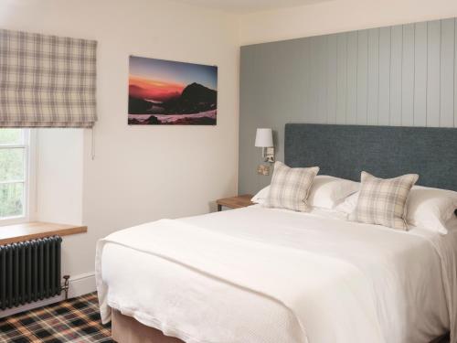 a bedroom with a large white bed and a window at The Bryntirion Inn in Llandderfel