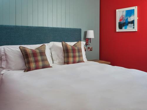 a white bed with two pillows and a red wall at The Bryntirion Inn in Llandderfel