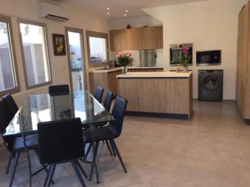 une cuisine avec une table en verre et des chaises dans une pièce dans l'établissement Duplex with Garden in Palm Beach Croisette, à Cannes
