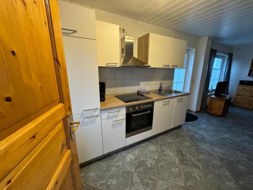 a kitchen with white cabinets and a stove top oven at Hotel Panorama in Wees