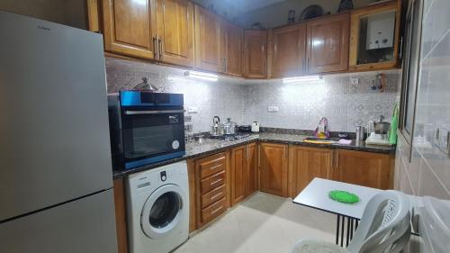 a kitchen with wooden cabinets and a washer and dryer at Séjour confort 2 Wifi fibre optique & parking gratuit-Netflix in Midelt
