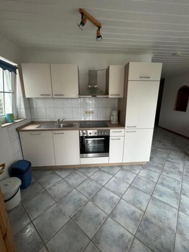 a kitchen with white cabinets and a stove top oven at Hotel Panorama in Wees
