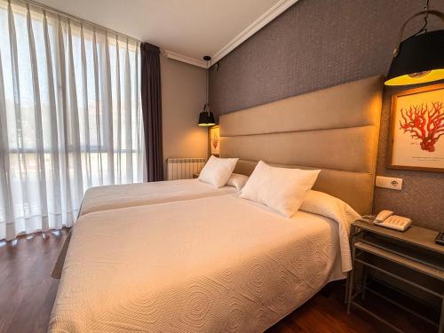 a hotel room with two beds and a window at Hotel Verdemar in Ribadesella