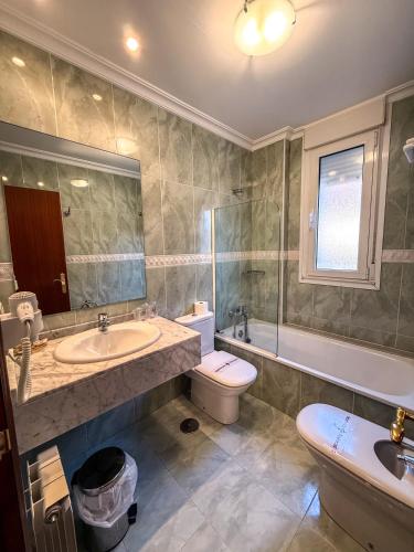 a bathroom with a sink and a toilet and a tub at Hotel Verdemar in Ribadesella
