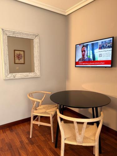 a table and two chairs and a television on a wall at Hotel Verdemar in Ribadesella