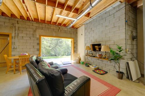 a living room with a leather couch and a brick wall at Creek Access Quiet Bryson City Retreat with Hot Tub in Bryson City