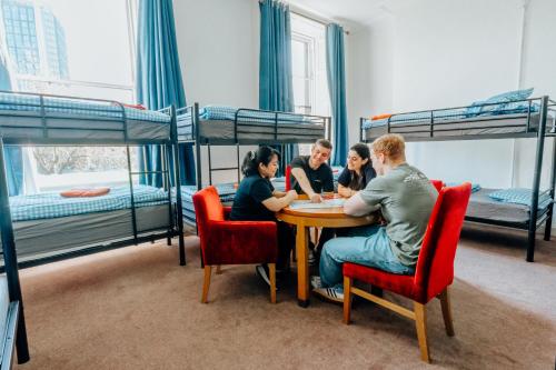 a group of people sitting around a table in a room with bunk beds at Eden Quay Guesthouse Private Rooms in Dublin