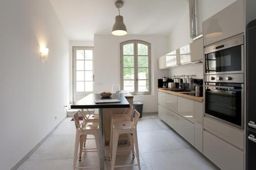 une cuisine avec des armoires blanches et une table avec des chaises dans l'établissement Appartement Le Belise, à Arles
