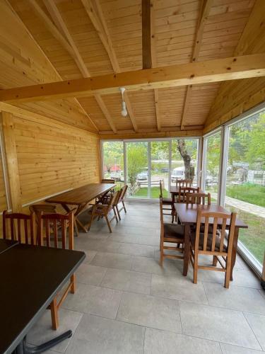 a dining room with tables and chairs and windows at Bujtina Arlindi in Valbonë