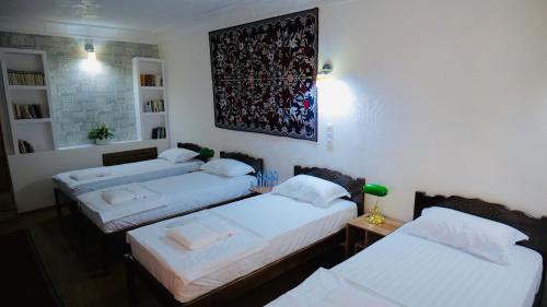 a room with three beds and a picture on the wall at MUSLIMA HOTEL Boutique in Bukhara