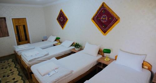 four beds in a room with white sheets at MUSLIMA HOTEL Boutique in Bukhara