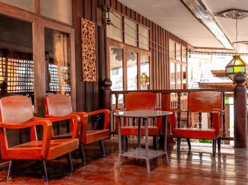 a restaurant with red chairs and a table and a table and chairs at Rak Chiang Mai Guesthouse in Chiang Mai