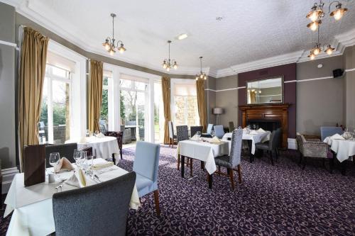 Halifax Hall في شيفيلد: غرفة طعام مع طاولات وكراسي ومدفأة