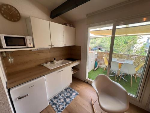 Il comprend une cuisine équipée d'un évier, d'un four micro-ondes et d'une table. dans l'établissement MER ET SOLEIL Joli studio cabine mezzanine COSY Mt St Martin Cap d'Agde, au Cap d'Agde