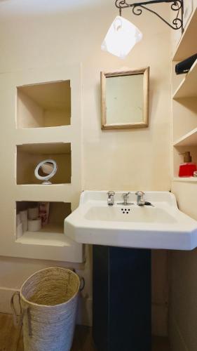 La salle de bains est pourvue d'un lavabo, d'un miroir et d'un panier. dans l'établissement La Bohème Saint Michel by Art&Suites, à Gaillac