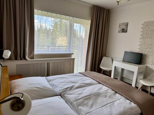 a bedroom with a bed and a desk and a window at Wellness Apartmán Monika - Tatranská Štrba in Štrba