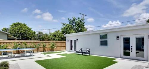 a backyard with a white house with a green lawn at Lytle Palm Villa in West Palm Beach