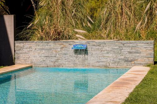 - une piscine avec un mur en pierre et de l'eau bleue dans l'établissement Manadelmar, à Las Gaviotas