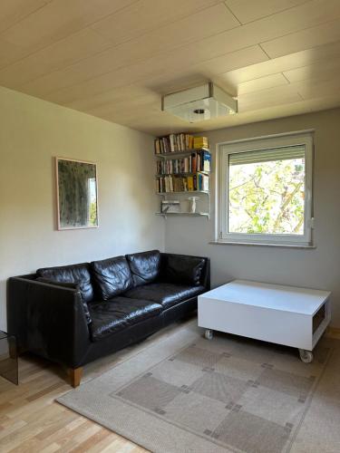 a living room with a black leather couch and a white coffee table at RIO INN in Großbottwar