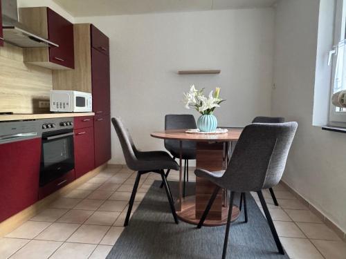 a kitchen with a table with chairs and a vase of flowers at Bensersiel Ferienwohnung Kapitän mit Terrasse und Garten in Bensersiel