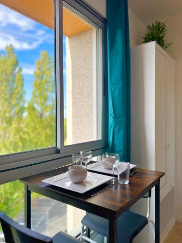 une table en bois avec des bols à côté d'une fenêtre dans l'établissement Le Maritime - Proche plage, Wifi, à Vaux-sur-Mer