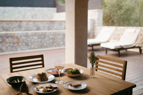 a wooden table with plates of food and a glass of wine at Ca'n Beneït in Binibona