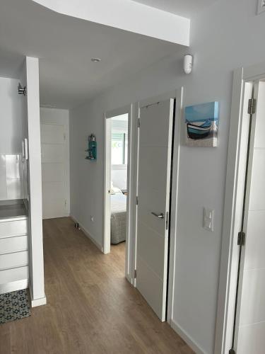 a room with white walls and a bedroom with a bed at Marina3 - Playa de Daimús - Ganador Traveller Awards 2026 in Daimuz
