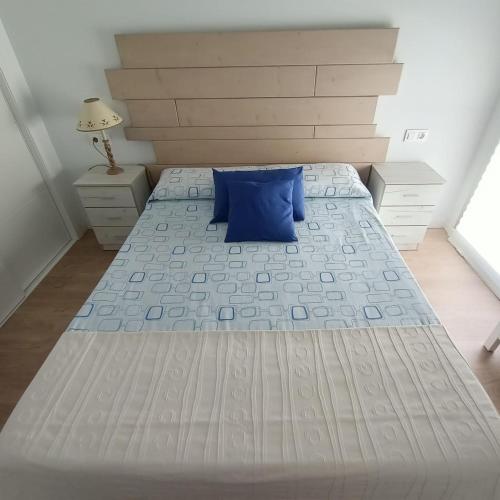a bedroom with a large bed with a blue pillow at Marina3 - Playa de Daimús - Ganador Traveller Awards 2026 in Daimuz