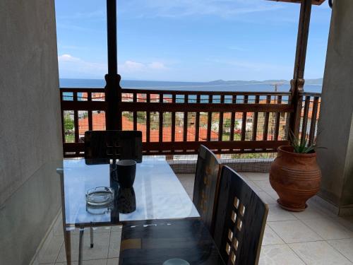 a glass table on a balcony with a view of the ocean at Sweet Home Nea Roda! in Nea Roda