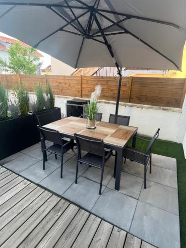 une table et des chaises en bois sous un parasol sur une terrasse dans l'établissement Chalet cosy atypique, à Vichy