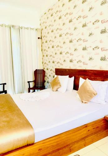 a bedroom with a large white bed with a wall at Royal Retreat ,Kandy in Kandy