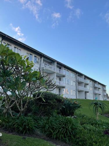 an apartment building with a tree in front of it at Jakaranda 22 apartment, Uvongo in Uvongo Beach