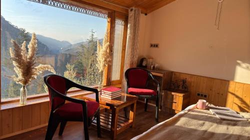 a bedroom with two chairs and a table and a window at Kaushalya Homes in Shimla