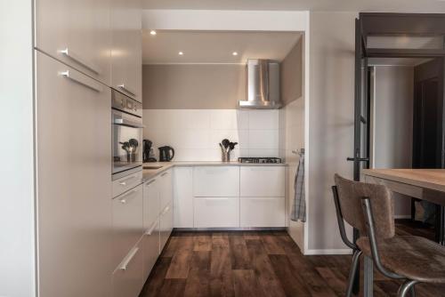 a kitchen with white cabinets and a wooden table at Zuiderzeestate 35, prachtig appartement aan het IJsselmeer in Makkum