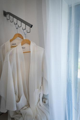 a white dress hanging on a rack next to a window at Sandy Beach in Agia Marina Aegina
