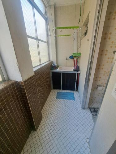 baño con lavabo y suelo de baldosa. en Apartamento Aconchego check-in e check-out flexíveis, en Guarujá