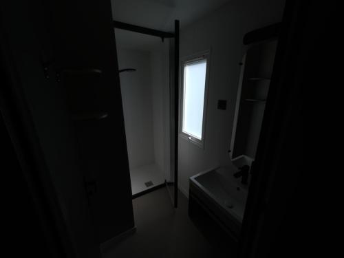 - une salle de bains sombre avec lavabo et fenêtre dans l'établissement Mobil-Home tout équipé, à Pont-Noyelles