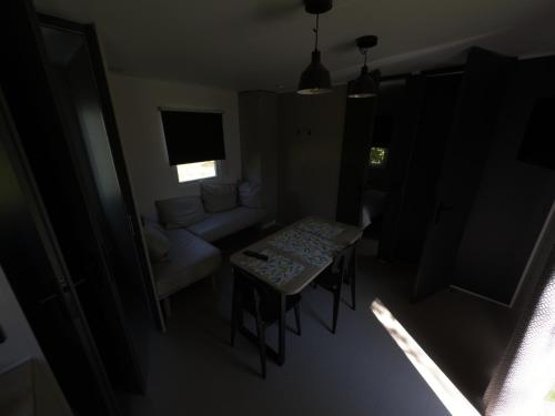- un salon sombre avec une table et un canapé dans l'établissement Mobil-Home tout équipé, à Pont-Noyelles