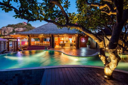 a swimming pool with a tree in front of a house at Davinia Hua Hin Resort in Hua Hin